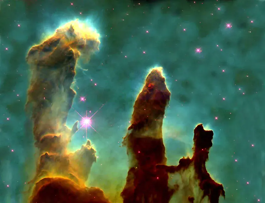 The Pillars of Creation in the Eagle Nebula, towering columns of dark dust and gas sculpted by starlight, imaged by Hubble