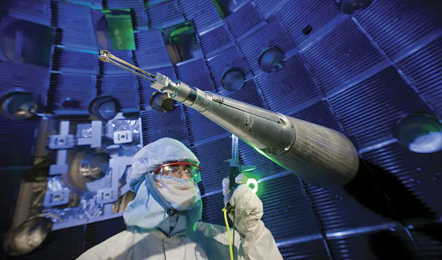 A technician working inside the ten-metre spherical target chamber of the National Ignition Facility, studded with laser ports
